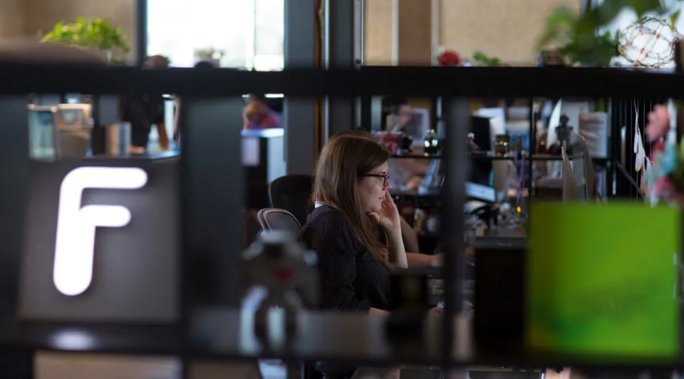 The Forge logo in the foreground, with Nicole Benz working in the background