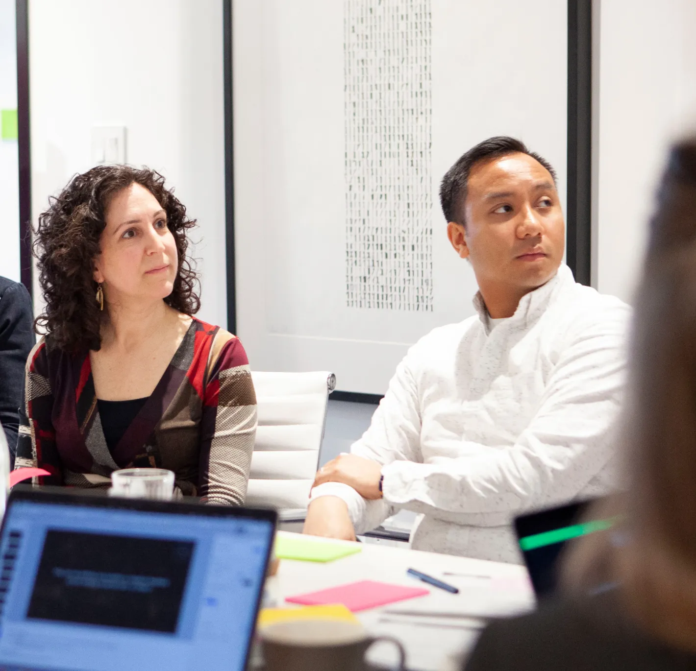 Two people sitting in a boardroom.