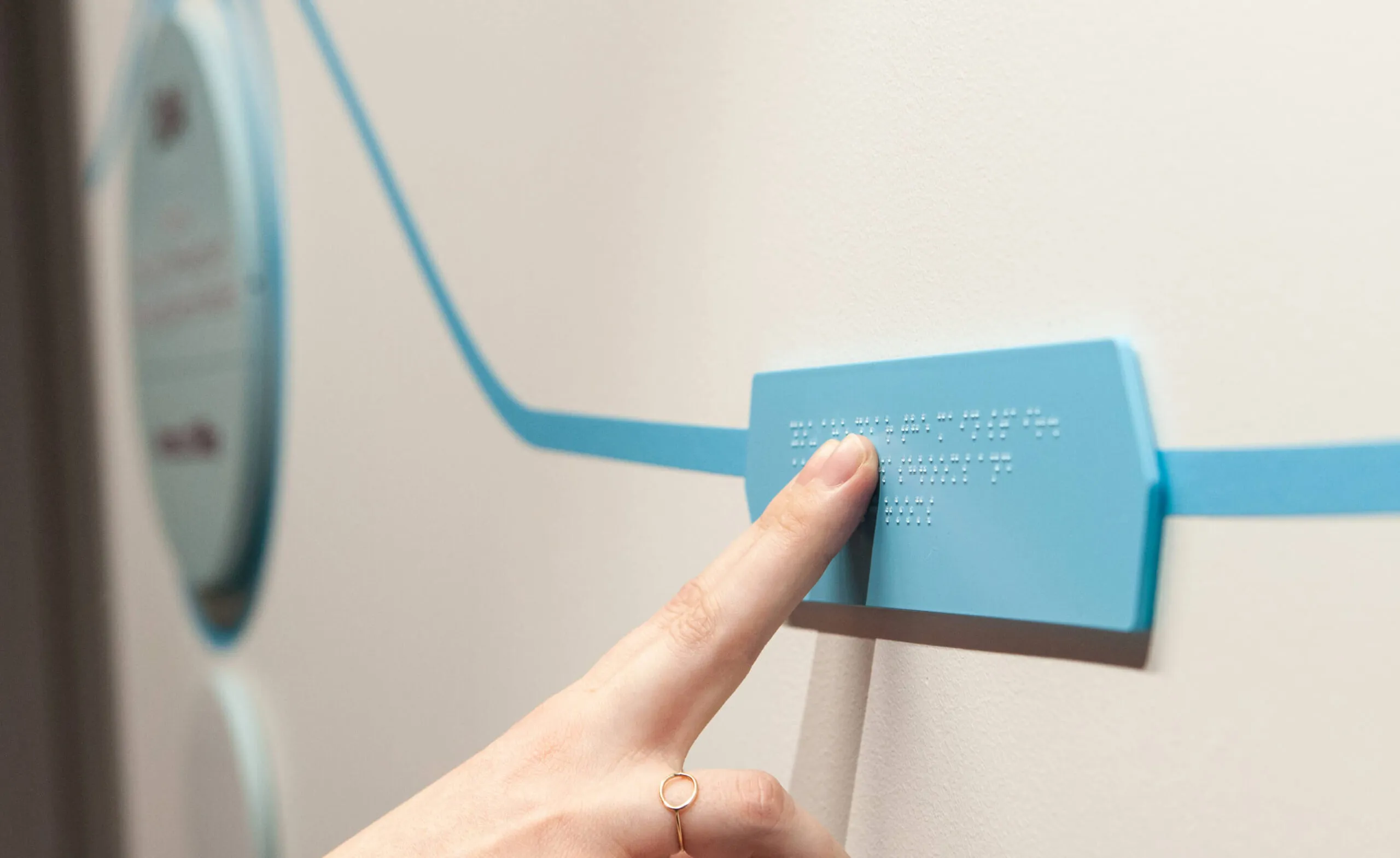 A person's hand touching a braille sign.