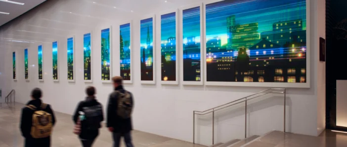 The lobby of an office building showing digital art on the walls of a cityscape