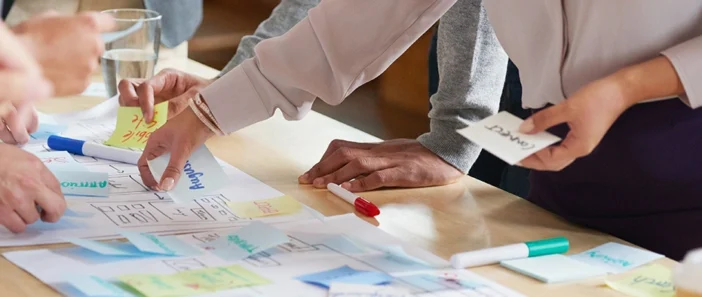 Hands moving post it notes on a boardroom table